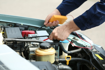 Mechanic hands with scan tool diagnosing car in open hood. Closeup