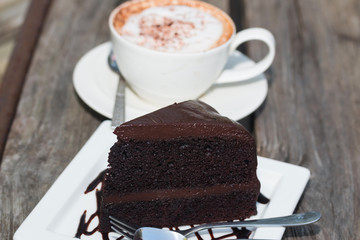 chocolate cake with coffe on plate on wood table
