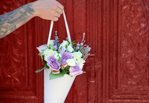 Male hand holding beautiful bouquet on door background