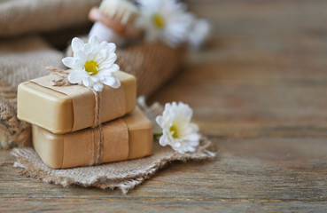Fototapeta na wymiar Spa concept. Soap and daisy flowers on wooden table