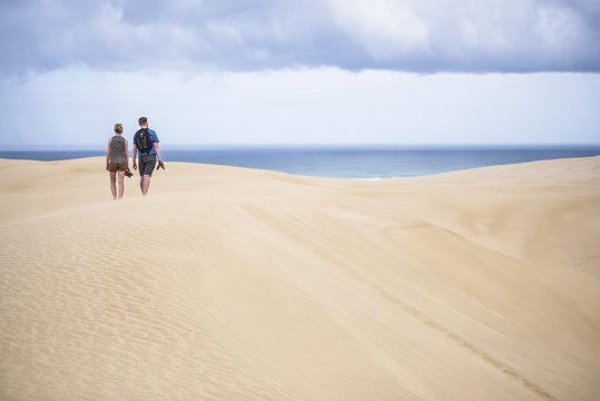 Two tourists at Te Paki Sand Dunes on 90 Mile Beach, Northland, New Zealand