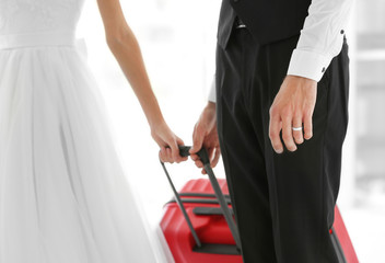 Fototapeta na wymiar Groom and bride with big suitcase indoors