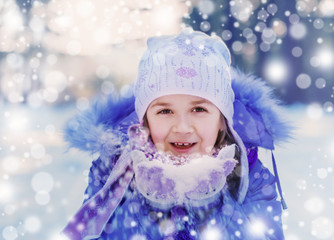 Happy child having fun playing with snow in winter day