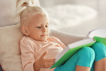 Small girl reading book on couch