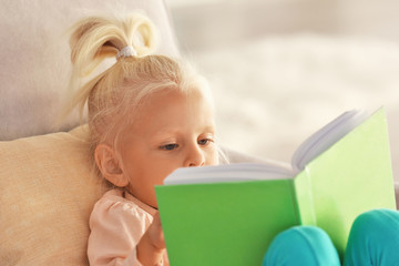 Small girl reading book on couch