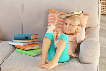 Small girl plying with book at home