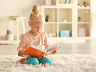 Small girl reading book on carpet