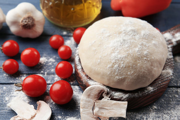 Fototapeta na wymiar Raw pizza dough with ingredients on wooden table