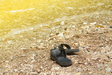 Black sandals are put down on riverside. Artificial light was added on the top left corner for warm tone style.