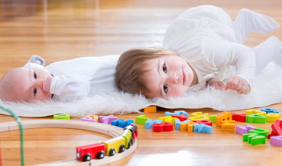 Happy toddler girl playing with her baby sister