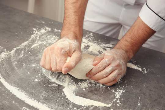 Male hands preparing dough for pizza on table closeup