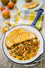 Chantarelle mushrooms on a frying pan on wooden rustic background. 