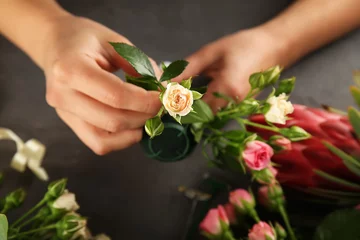 Cercles muraux Fleuriste Mains féminines faisant un beau bouquet de fleurs sur fond sombre