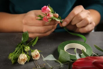 Photo sur Plexiglas Fleuriste Female hands making beautiful bouquet of flowers on dark background