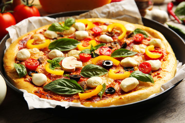 Fresh pizza with tomatoes, cheese and mushrooms on wooden table closeup