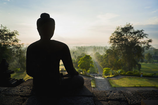 Stone Buddha silhouetted at sunrise at Borobudur Temple, Java, Indonesia