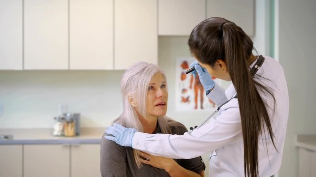 An older woman gets help for her sickness at a doctors office. A medical professional helps an elderly woman. 