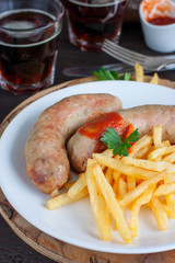 Sausages and potatoes with dark beer on a wooden table, selective focus