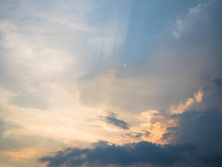 Picture of the sunset cloudy sky reflecting orange sun rays. Background of the sunset sky with sun rays reflecting from the clouds.