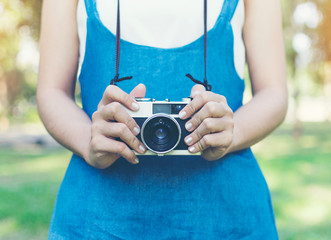 Fototapeta premium vintage autumn photo with girl standing in a park with old camera.