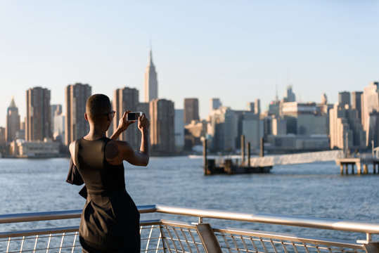 African business woman taking picture on the phone outdoor, New York, Manhattan, skyline view