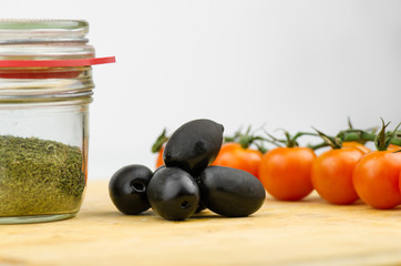 Fresh Olives, Cherry Tomatoes And Herbs In a Jar On Wooden Table Closeup