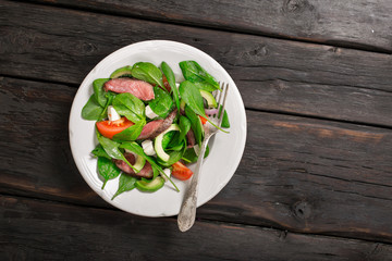 Plate with a grilled meat salad with a fork