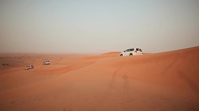 ABU DHABI, UAE - AUGUST 20, 2014: Desert Safari SUVs bashing through the arabian sand dunes