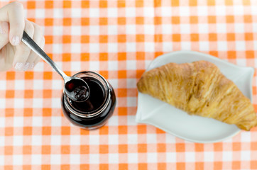 Tasty Butter Croissant And Jar Of Sweet Cherry Jam Breakfast On Plaid Table Cover Close Up Spoon