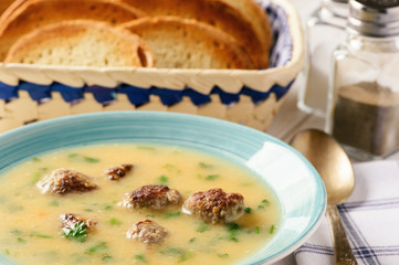 Vegetable cream soup with meatballs on white wooden background.