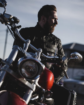 Portrait of biker sitting on motorcycle and looking away