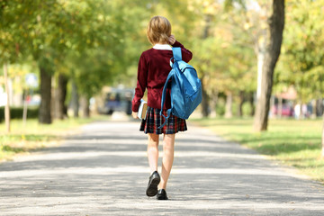 Schoolgirl walking along alley in green park