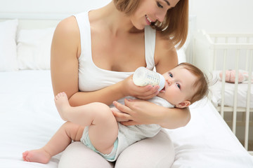 Mother holding and feeding baby from bottle