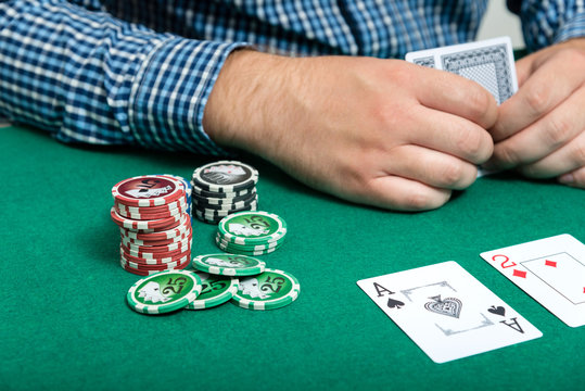 chips and cards for poker in hand on green table