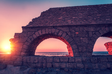 Remains of the ancient Roman aqueduct in ancient city Caesarea at sunset. Israel.