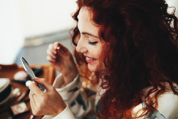 Obraz premium beautiful young woman with red curly hair doing makeup