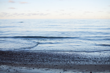 Abstract background of a pastel sunset on a peaceful sea with calm waves wafting to the shore 