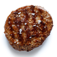 Single grilled hamburger patty with salt isolated on white from above.