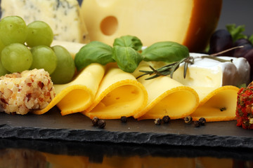 Cheese platter with different cheese and grapes - some emmental, gauda, parmesan and brie  cheese on a table for brunch