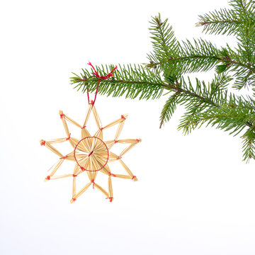 halm stjärna hänger i julgran med vit bakgrund