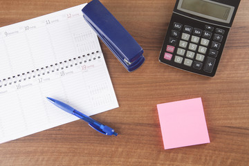 Workplace in office with calendar, pen, calculator and post it