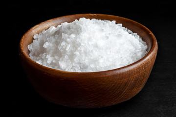 Fototapeta na wymiar Coarse salt in wooden dish isolated on black.