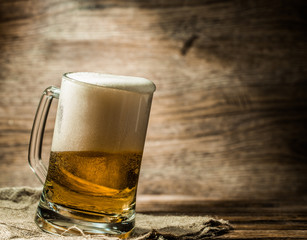 Foamy beer poured into mug standing on table