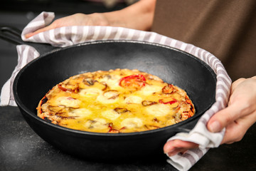 Woman holding freshly baked pizza in a pan