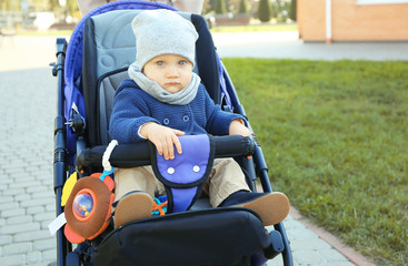 Cute little baby sitting in stroller outdoors