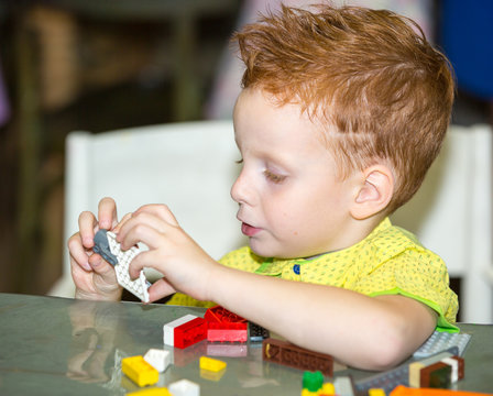 Boy child playing with the constructor blocks in preschool at the table in kindergarten