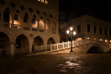 Fototapeta premium bridge via the Palace channel, a lamp and a wall of Doges Palace at night during a rain, Venice