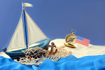 Wooden boat, compass and USA flag on blue background. Columbus Day concept