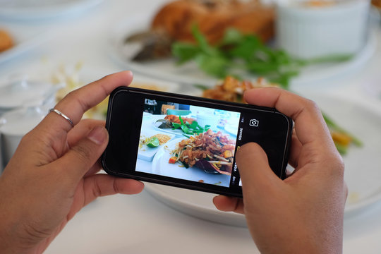 Using hands to take food's picture by smart phone.