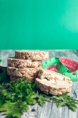 Pieces of crispbread near measuring tape and green arugula on grey background. Diet concept. Healthy food.